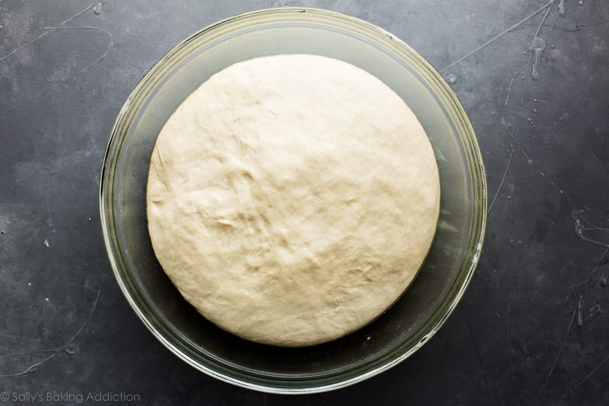 pretzel roll dough in a glass bowl after rising