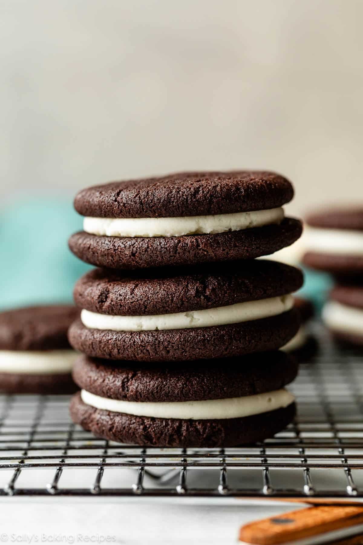 stack of 3 homemade Oreos with cream filling on cooling rack.