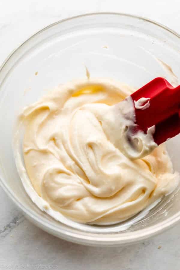 lemon cream cheese frosting in glass bowl with red spatula.