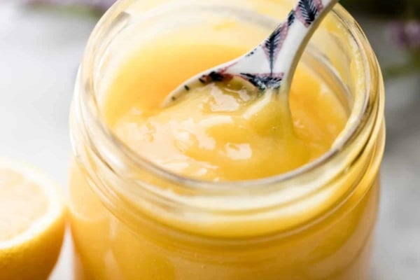 Lemon curd in a glass jar with spoon