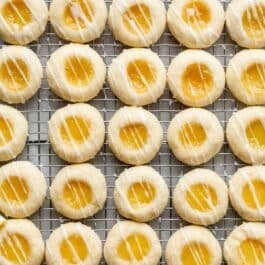 lemon curd thumbprint cookies with icing on cooling rack.