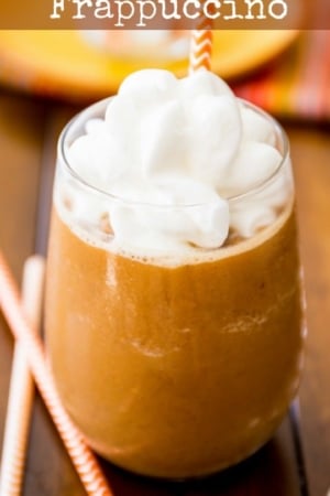 pumpkin frappuccino in a glass with whipped cream and a straw