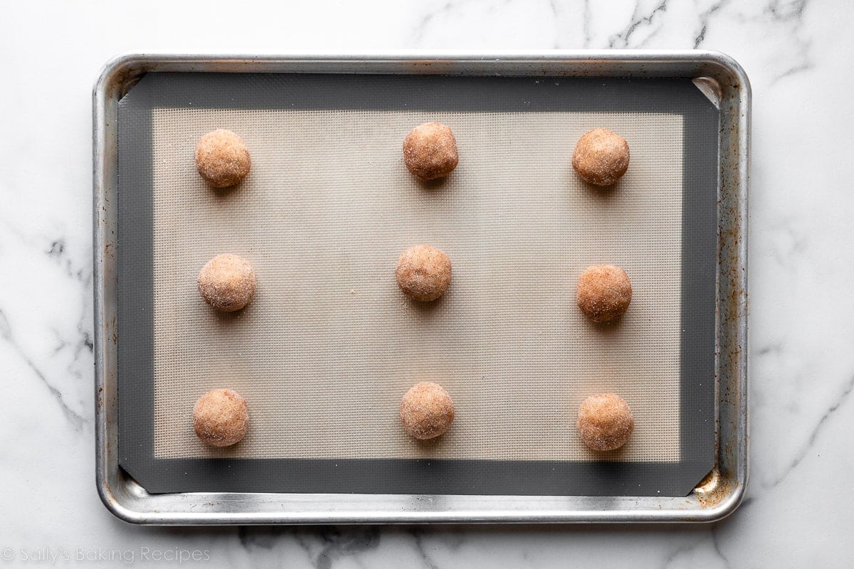 snickerdoodle cookie dough balls on lined baking sheet.